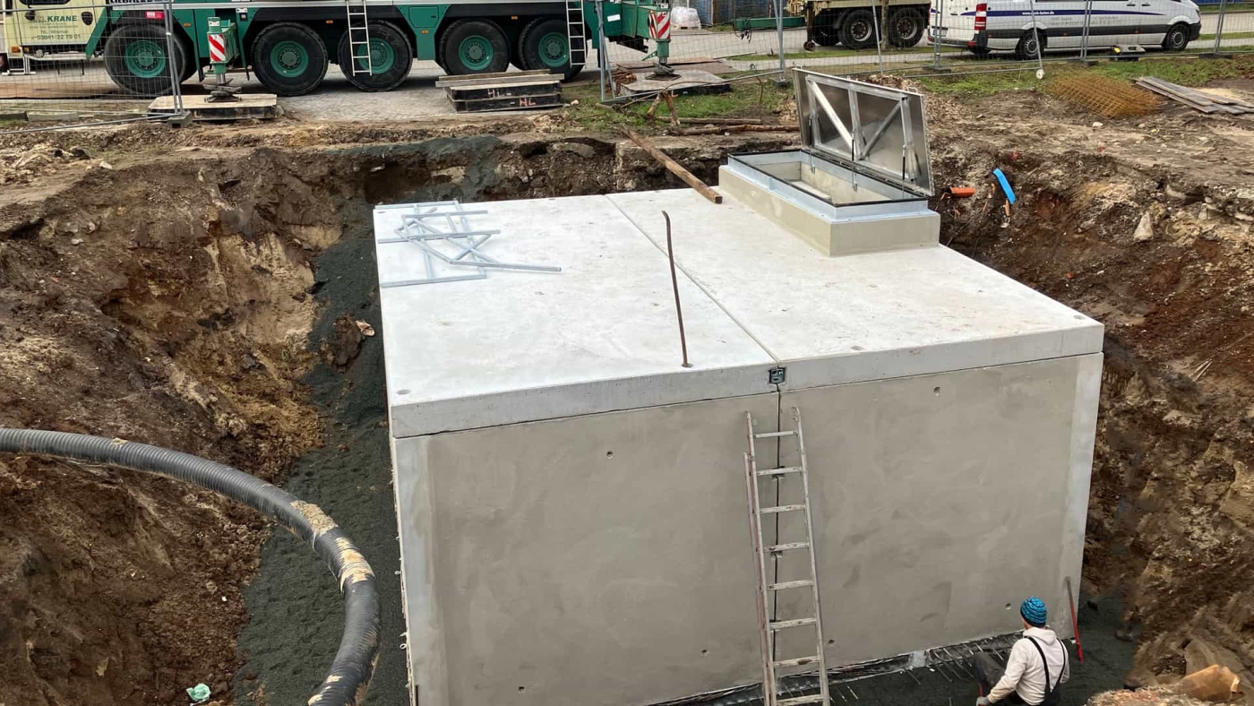 Installation eines unterirdischen Betonkubus mit technischen Anlagen auf einer Baustelle.